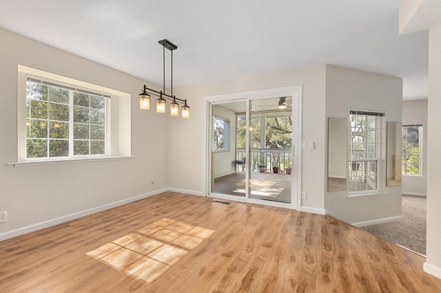 unfurnished dining area with plenty of natural light, baseboards, and wood finished floors