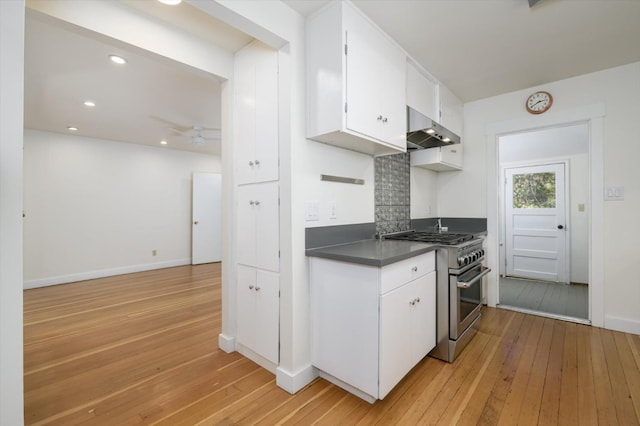kitchen with high end stainless steel range, dark countertops, range hood, and light wood-type flooring