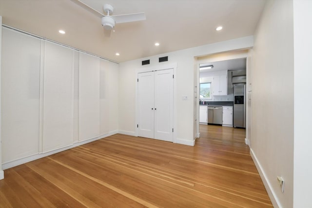 unfurnished bedroom with stainless steel refrigerator with ice dispenser, light wood-style flooring, visible vents, and recessed lighting