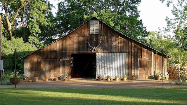 view of barn with driveway and a yard