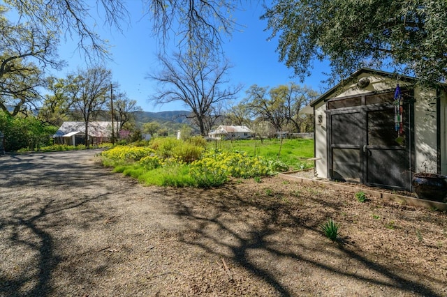 view of yard featuring an outdoor structure, a mountain view, and a shed