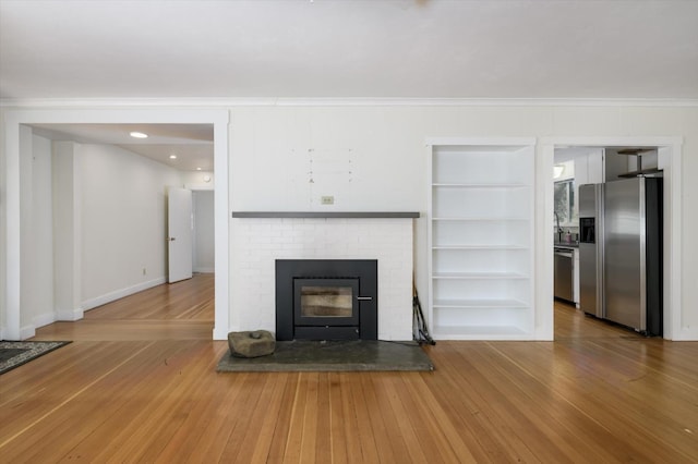 unfurnished living room with light wood-style floors, crown molding, baseboards, and ceiling fan