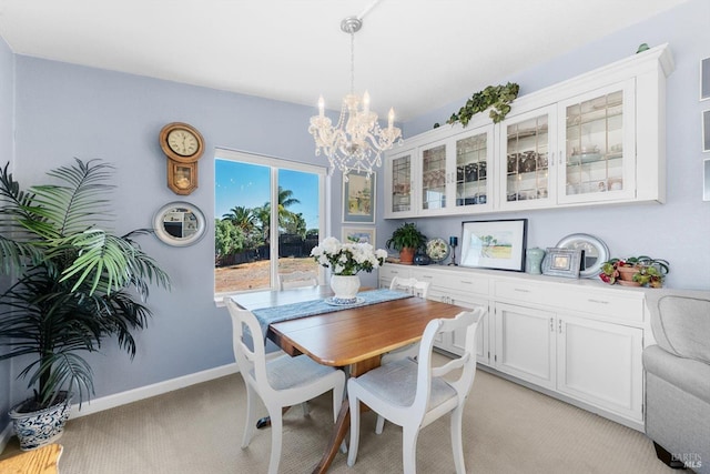 dining space with baseboards, light colored carpet, and an inviting chandelier