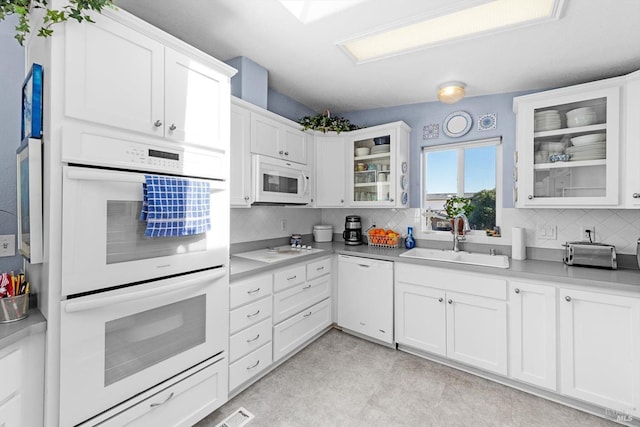 kitchen with tasteful backsplash, white appliances, white cabinetry, and a sink