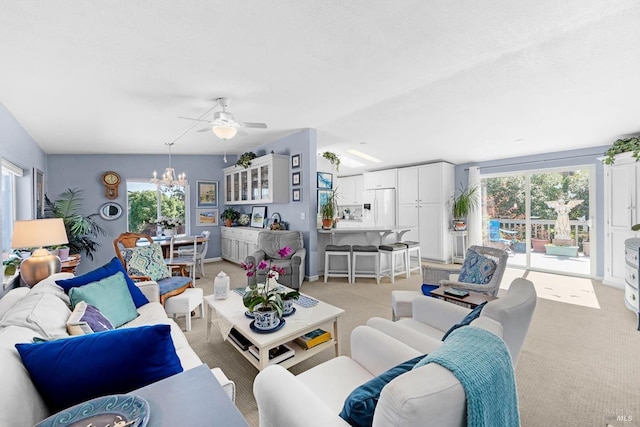 living room with light carpet, a healthy amount of sunlight, and ceiling fan with notable chandelier