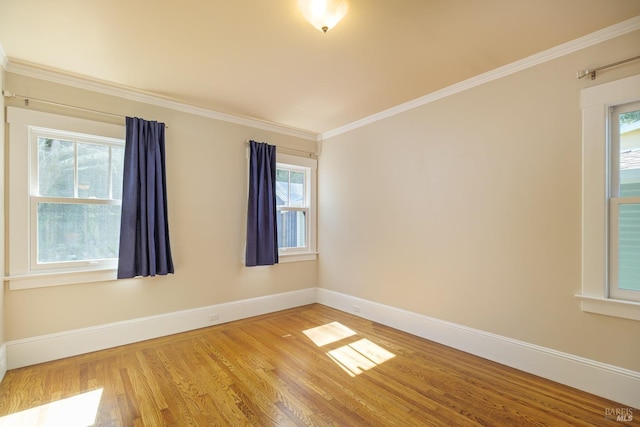 empty room with ornamental molding, baseboards, and wood finished floors