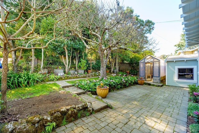 view of patio / terrace with fence, a greenhouse, and an outdoor structure