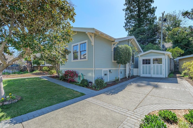 view of side of home with driveway, fence, an outdoor structure, and a yard