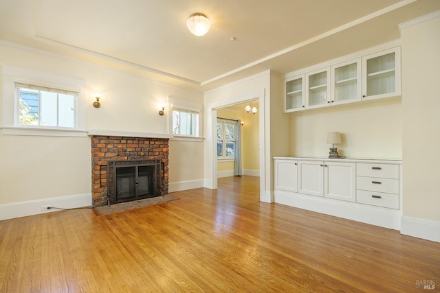 unfurnished living room with crown molding, a fireplace, light wood-style flooring, and baseboards