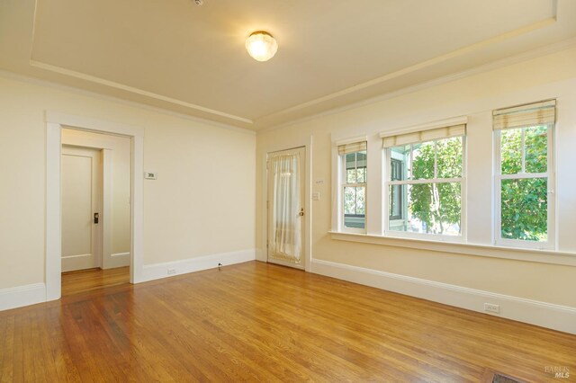 unfurnished room featuring crown molding, baseboards, and wood finished floors