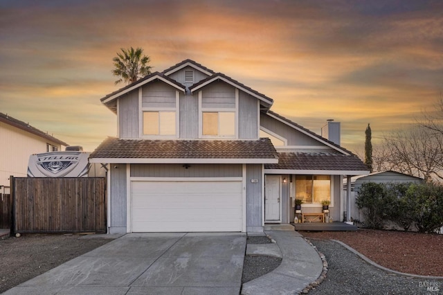 traditional home with concrete driveway, a tiled roof, fence, a porch, and a garage