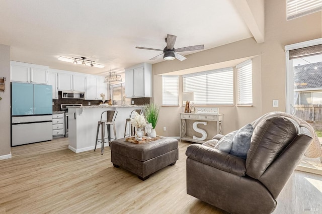 living room with light wood finished floors, beam ceiling, and ceiling fan