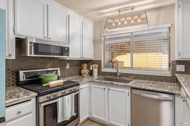 kitchen featuring white cabinets, decorative backsplash, a sink, and appliances with stainless steel finishes