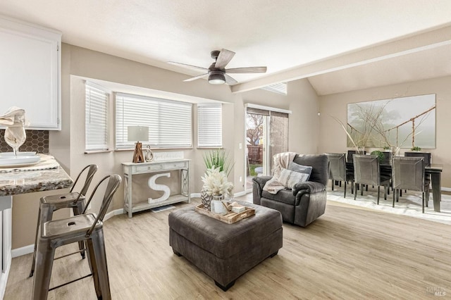 living room featuring light wood finished floors, a ceiling fan, baseboards, and lofted ceiling