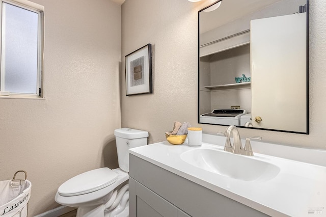 half bath with a textured wall, vanity, a healthy amount of sunlight, and toilet