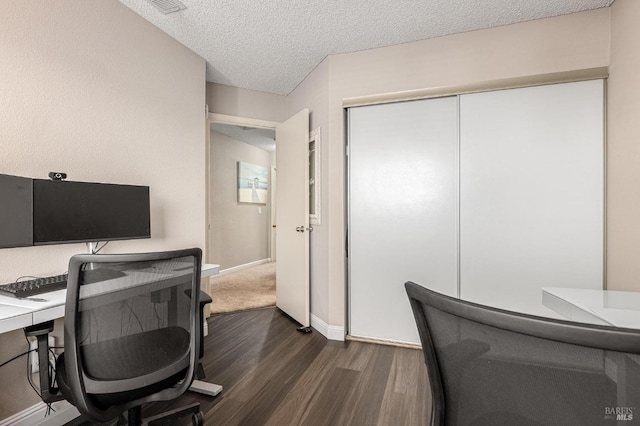 office area featuring baseboards, visible vents, dark wood-type flooring, and a textured ceiling