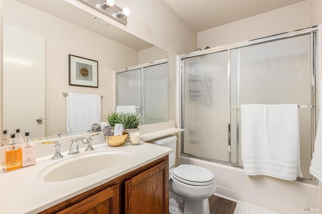 full bathroom featuring toilet, vanity, wood finished floors, and shower / bath combination with glass door