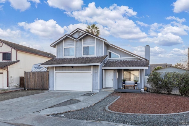 traditional home featuring a tiled roof, covered porch, concrete driveway, fence, and an attached garage