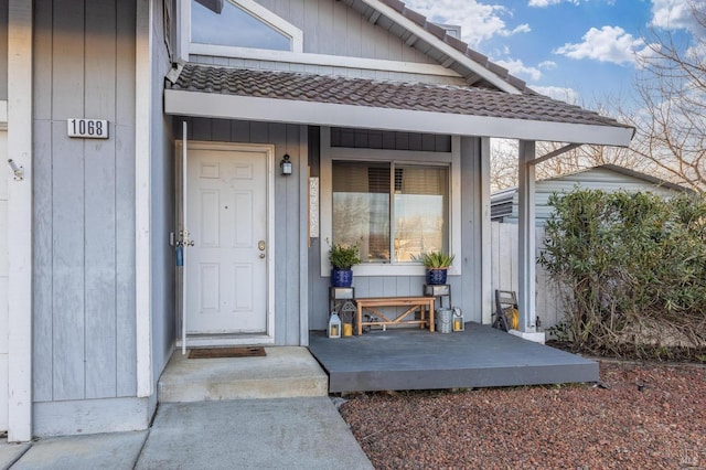 view of exterior entry featuring a tile roof and covered porch