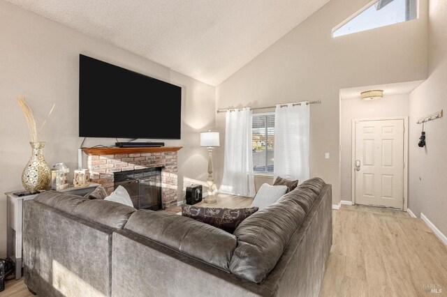 living area with high vaulted ceiling, baseboards, a brick fireplace, and wood finished floors