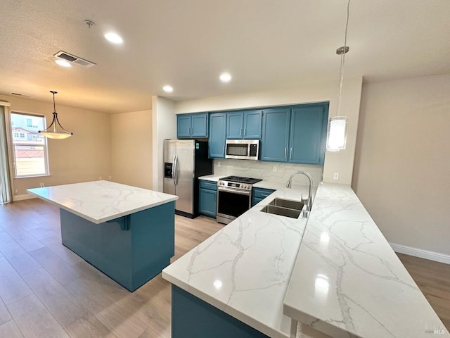 kitchen with visible vents, appliances with stainless steel finishes, a sink, light stone countertops, and blue cabinets