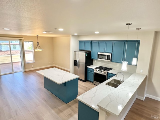 kitchen featuring stainless steel appliances, a sink, light wood-style flooring, and blue cabinets