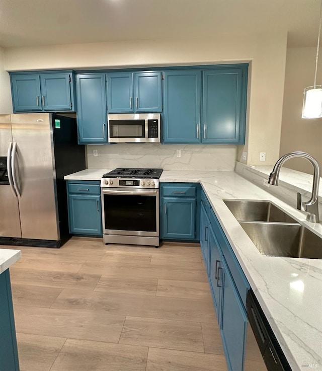 kitchen featuring appliances with stainless steel finishes, a sink, and blue cabinetry