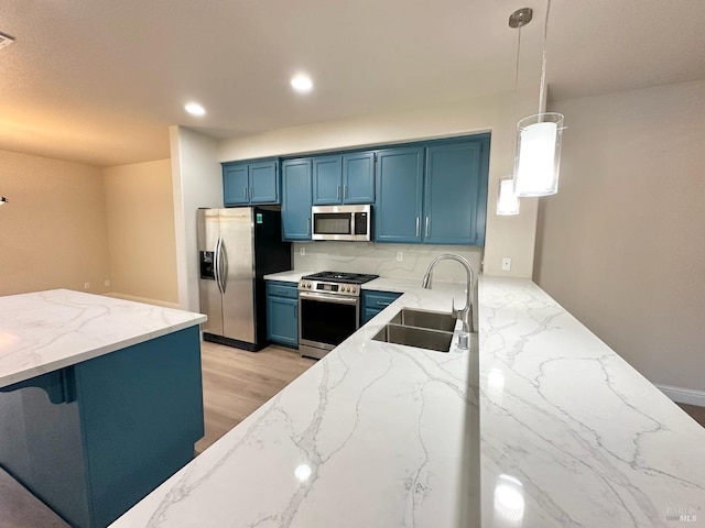 kitchen with appliances with stainless steel finishes, blue cabinets, light stone countertops, a sink, and recessed lighting