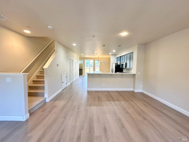 unfurnished living room with light wood-style flooring, stairway, baseboards, and recessed lighting