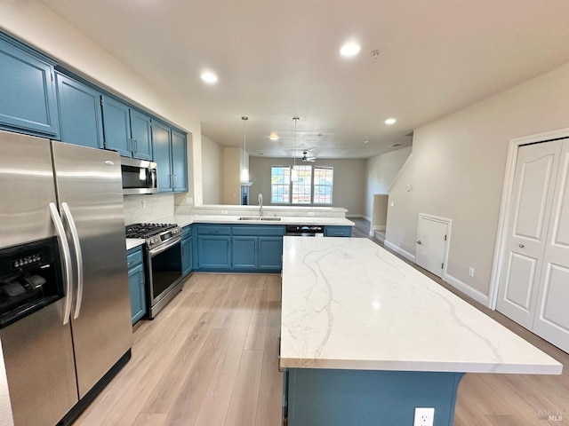 kitchen with stainless steel appliances, a peninsula, a sink, and blue cabinets