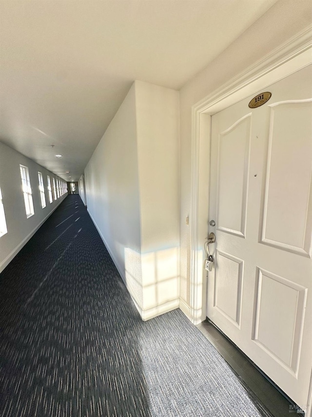 corridor with carpet floors and baseboards