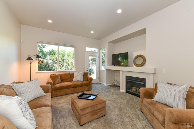 carpeted living room with recessed lighting, a glass covered fireplace, and baseboards