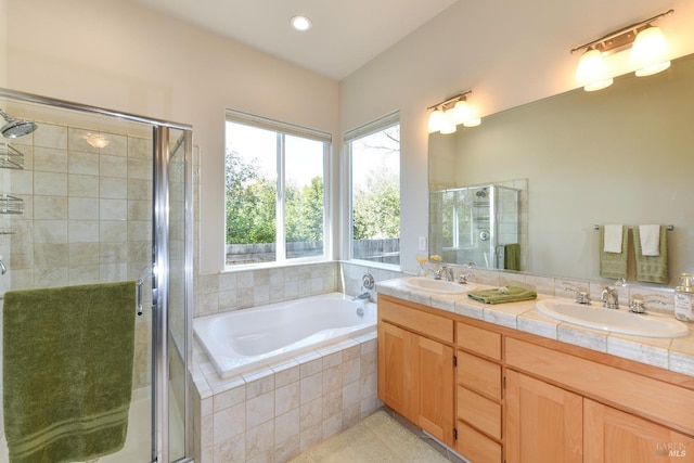 bathroom with a garden tub, a sink, a shower stall, and double vanity