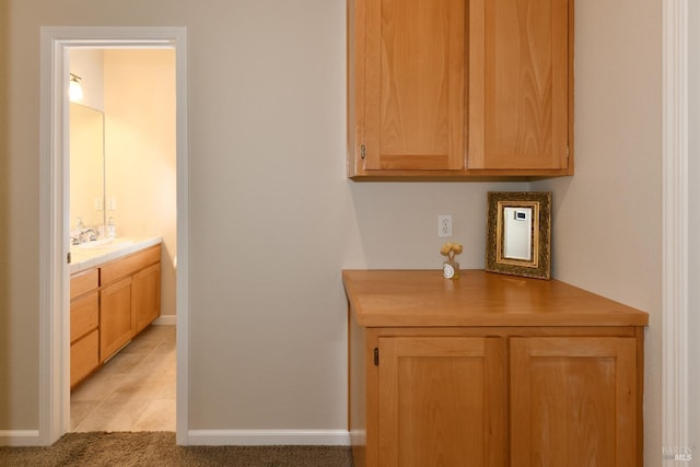 bar with light colored carpet, a sink, and baseboards