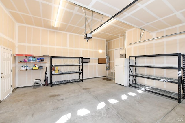 garage featuring gas water heater, freestanding refrigerator, and a garage door opener