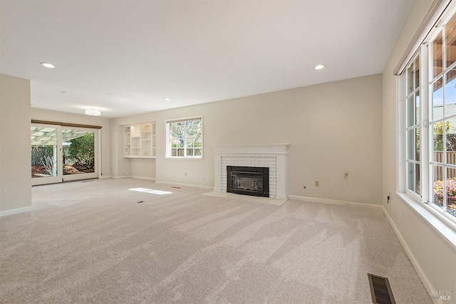 unfurnished living room with visible vents, baseboards, carpet, and a healthy amount of sunlight