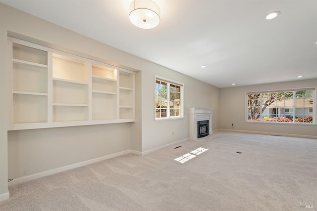 unfurnished living room with a fireplace with flush hearth, recessed lighting, baseboards, and carpet floors