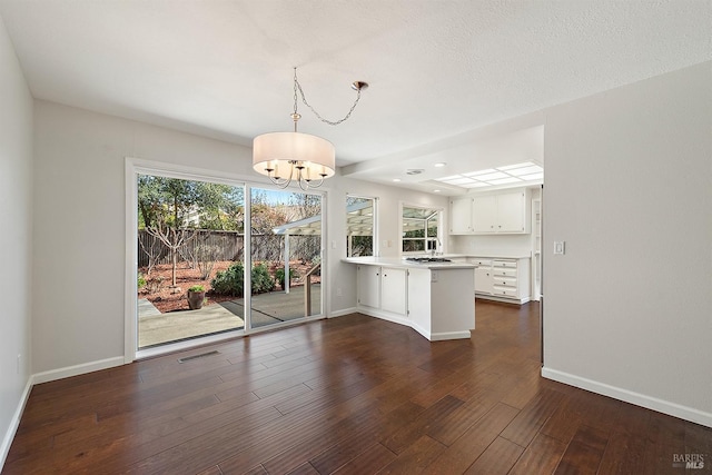 unfurnished dining area featuring dark wood-type flooring, baseboards, and visible vents