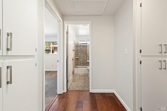 hall featuring baseboards, attic access, and dark wood-style floors