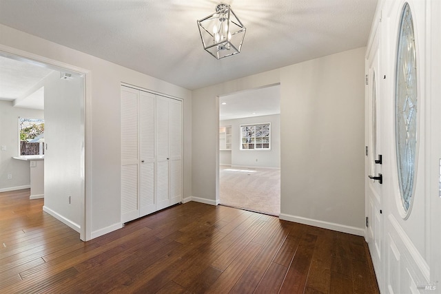 foyer featuring an inviting chandelier, baseboards, and hardwood / wood-style floors