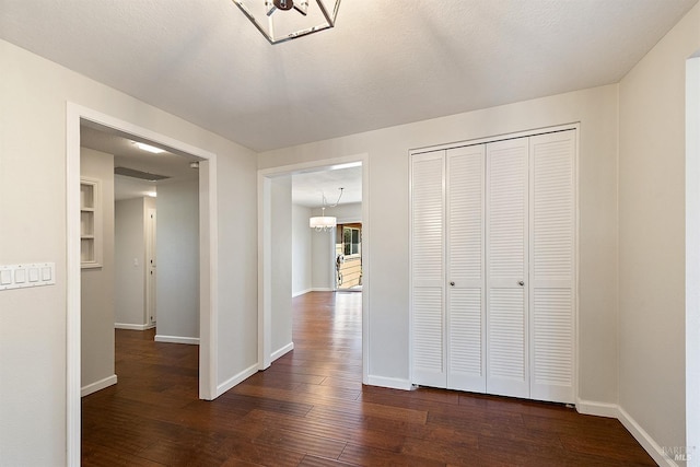 corridor with baseboards, a textured ceiling, and dark wood-style floors