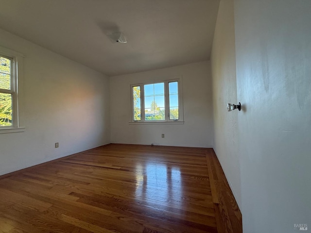 spare room with plenty of natural light and wood finished floors