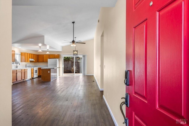 foyer entrance with dark wood-style floors, ceiling fan, baseboards, and vaulted ceiling