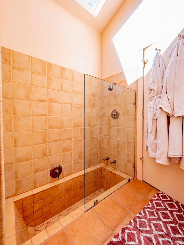 full bathroom featuring tile patterned floors, a skylight, and a tile shower