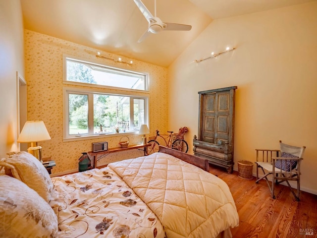 bedroom with wallpapered walls, ceiling fan, wood finished floors, and high vaulted ceiling