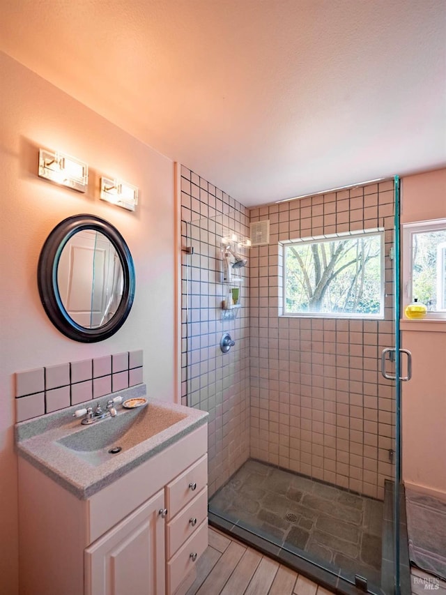 full bath with a stall shower, vanity, and wood finished floors