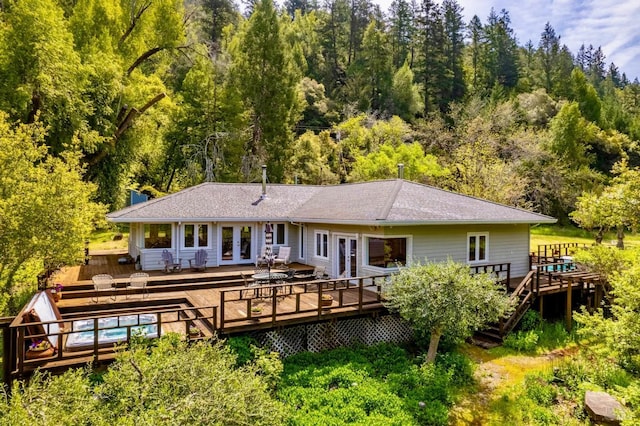 back of house featuring a forest view, french doors, a swimming pool, and a deck