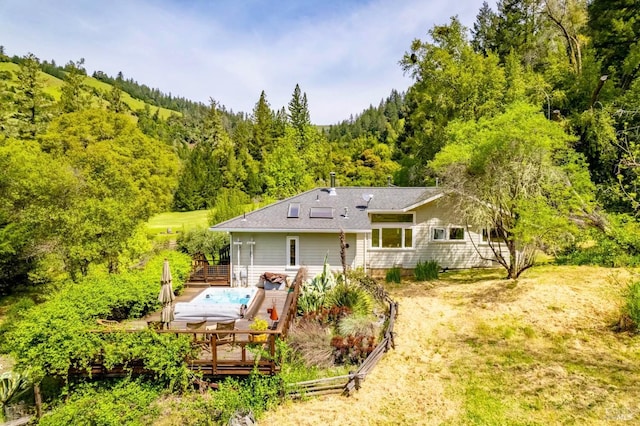 back of property featuring fence, a forest view, and a wooden deck