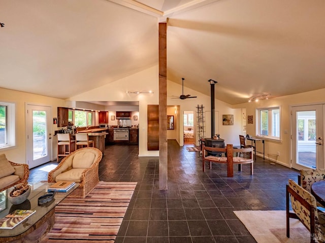 living room with a wealth of natural light, baseboards, vaulted ceiling with beams, and a wood stove