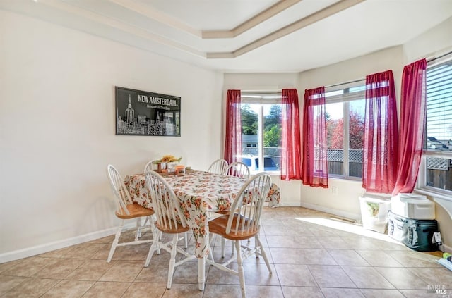 tiled dining room with baseboards and a raised ceiling